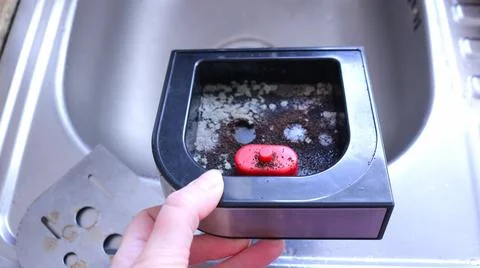 A dirty coffee machine drip tray with moldy ground coffee residue in hand. 库存照片