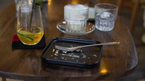 Dirty dish is seen laying on a table in a cafe, with empty glasses and a plate Stock Footage 238739877