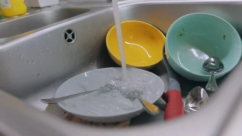 Dirty dishes in the sink. Routine in the kitchen. Tap water pours onto dirty Video stock 158701278
