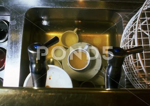 Dirty Dishes Soaking In Water In Sink, High Angle View