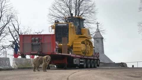 Dirty Dog Walking towards Camera in front of a Bulldozer and Church. Slow Motion Stock Footage 149322094