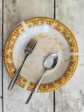 Dirty empty plate with fork and spoon after meal on rustic wooden table 库存照片