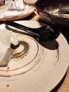 Dirty Empty Plates with Leftover Food and Used Napkins on Dining Table Stock Photos