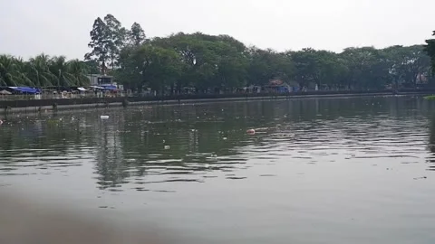 The dirty flow of the Cisadane River with murky colors and debris floating on it Video stock 303390352
