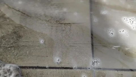 Dirty foam flows down the drain at a car wash Stock Footage 147028852