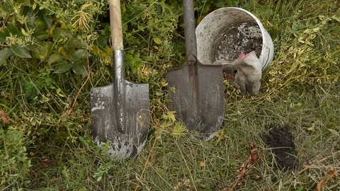 Dirty gardening tools: two shovels, a bucket and gloves on the grass Stock Footage 99533014