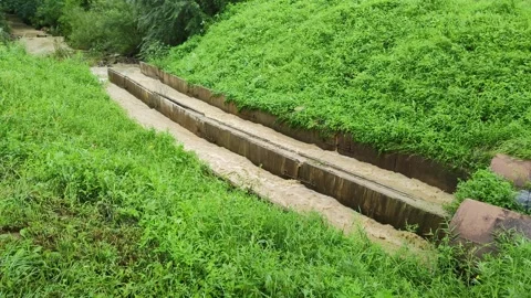 Dirty ground water flows out of pipes and flows through concrete drainage Stockbeeldmateriaal 253191048