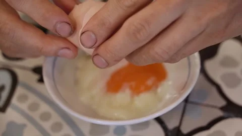 Dirty hands cracking an half boiled egg into a bowl over a patterned background 動画素材 317320622