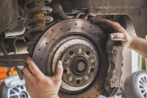 Dirty hands worker changing car brakes in a workshop Stock Photos