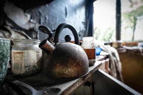 A dirty kettle sits on a kitchen table covered in soot and grime Stock Photos