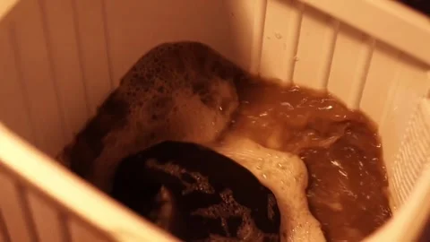 Dirty Laundry Agitating in Soapy Brown Water Inside Washer Tub Stock Footage 339029147