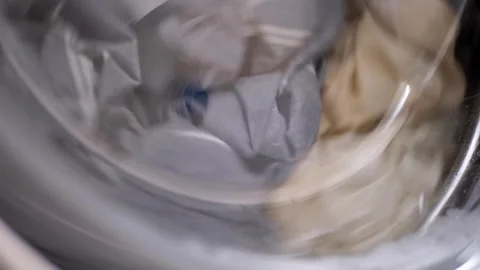 Dirty Laundry Tumbling Inside Modern Washing Machine Drum with Soap Stock Footage 338996327