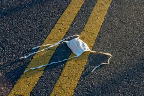 Dirty mask lying on the ground - sunset - Covid - 19 Stock Photos