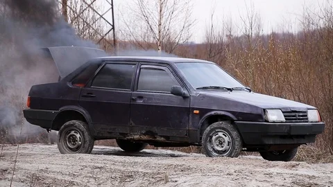 Dirty old car is left on deserted dust road with smoking open trunk on cold day. Stock Footage 106036849