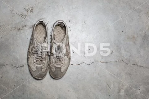 Dirty old shoes on concrete floor Stock Photos