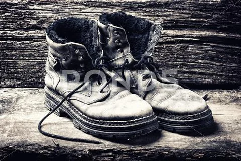 Dirty old shoes on wooden background . Vintage photo Stock Photos
