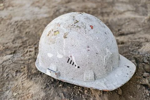 Dirty old work helmet left on the ground of construction site. Stock-Fotos