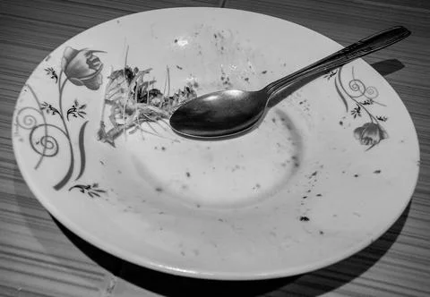 Dirty plate with fishbone leftovers and spoon Foto stock