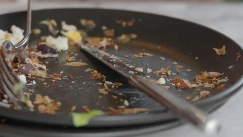 Dirty plate with fork and knife on table after eating close up slow motion .. Stock Footage 332139661