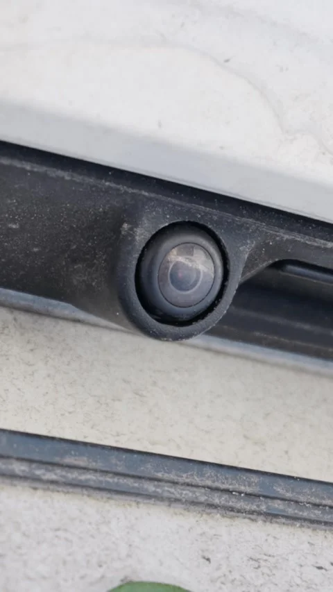 Dirty rear view camera lens mounted on white car bumper detail Stock Footage 329914309
