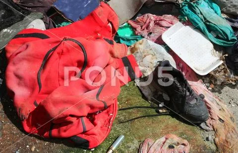 Dirty red sweatshirt and a black shoe with tatters in the homeless shelter Stock Photos