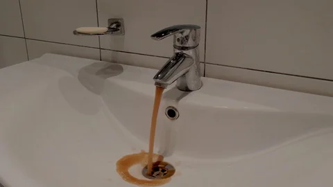 Dirty rusty brown water flows into a white sink. Unhealthy. Dirty poisonous Stock Footage 121281282