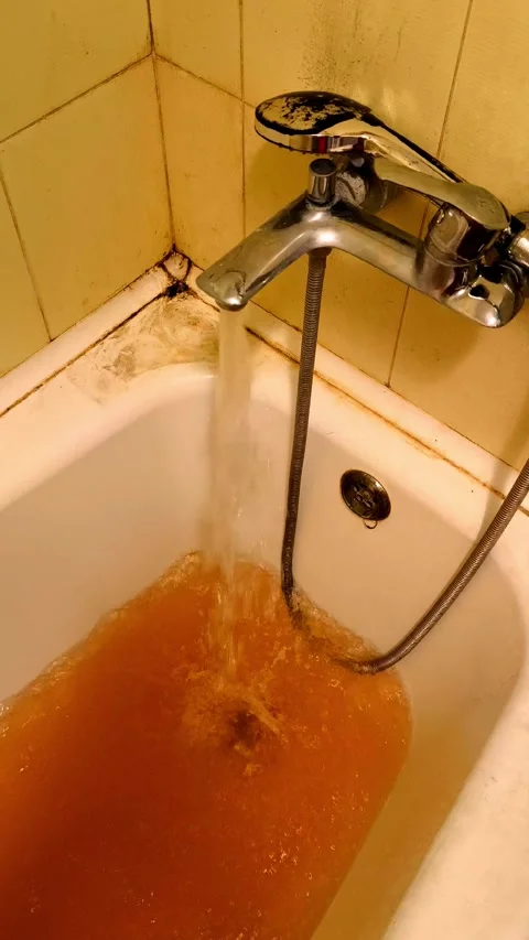 Dirty rusty brown water pouring from a metal faucet into a bathtub. Stock Footage 337679520