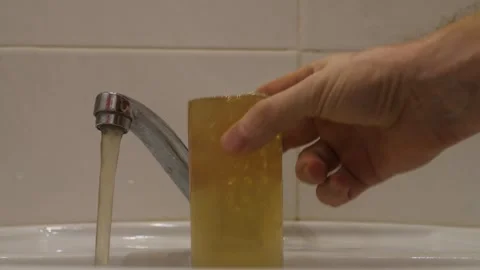 Dirty rusty drinking water flows from the tap in the apartment, a man pours.. Stock Footage 281412107