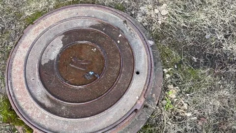 A dirty rusty iron hatch with a pattern is located next to dry grass during the Stock Footage 271231080