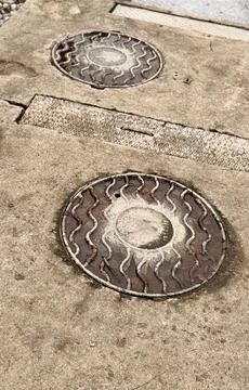 A dirty rusty iron hatch with a pattern is located next to dry grass during the Stock Photos