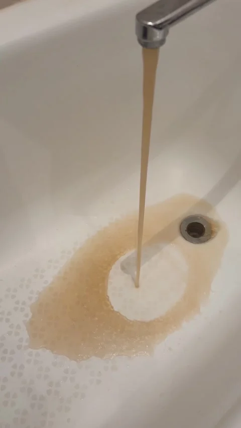 Dirty, rusty water flows out of a modern faucet, making the sink dirty.	 Stock Footage 317374696