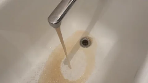 Dirty, rusty water flows out of a modern faucet, making the sink dirty.	 Stock Footage 317374698