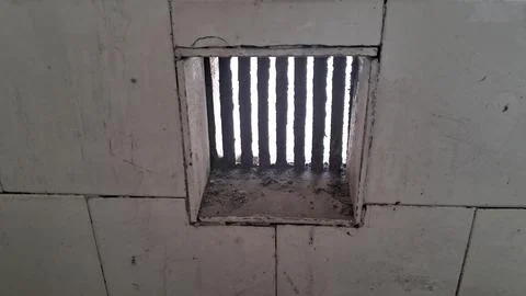 Dirty square ventilation grill set into a white tiled wall surface Stock Photos