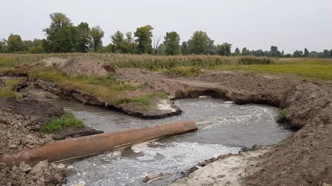 A dirty stream of water flows into the river Stock Footage 103173077