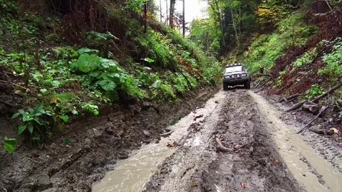 Dirty SUV driving in the dirt through muddy trail in the woods. Stock Footage 78626029