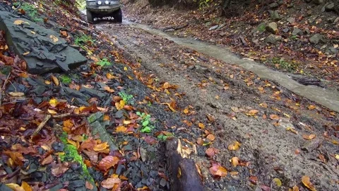 Dirty SUV driving in the dirt through muddy trail in the woods. Stock Footage 78626055