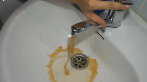 Dirty tap water. Faucet water runs in sink, starts out dirty rusty golden brown. Stock Footage