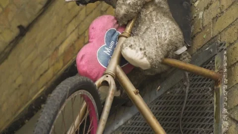 Dirty teddy bear left alone on a bike mounted creatively on the wall with Stock Footage 154571920