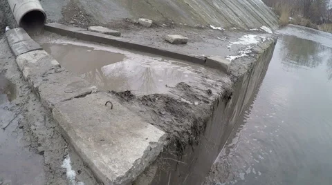 Dirty toxic waste water flows through  pipe to river, polluting it. Stock Footage 59122520