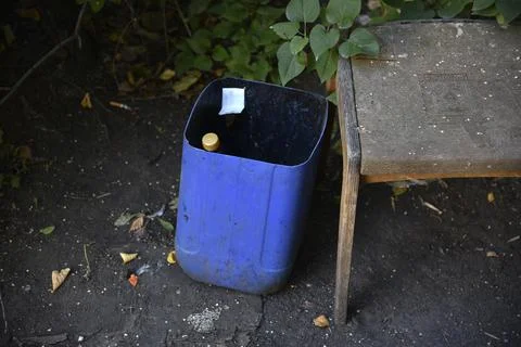 Dirty trash can in the yard. A garbage bin in the yard of the house in summer Stock Photos