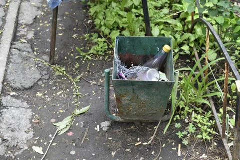 Dirty trash can in the yard. A garbage bin in the yard of the house in summer Stock Photos