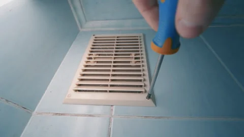 Dirty Ventilation Grille Unscrewing with Screwdriver on Blue Tile Floor | HVAC Stock Footage 333937559