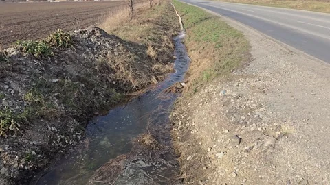 Dirty water flows from a powerful hose into a drainage ditch during flood r.. Video stock 330584170
