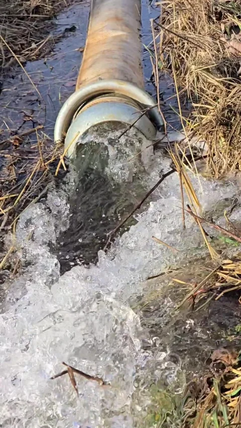 Dirty water flows from a powerful hose into a drainage ditch during flood r.. Stock Footage 331120568