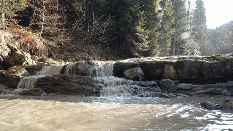 Dirty water running in a mountain stream. small waterfall on a bright sunny day Stock Footage 195309746