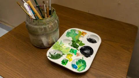 Dirty watercolor brushes set in a plastic container and color palette Stock Photos