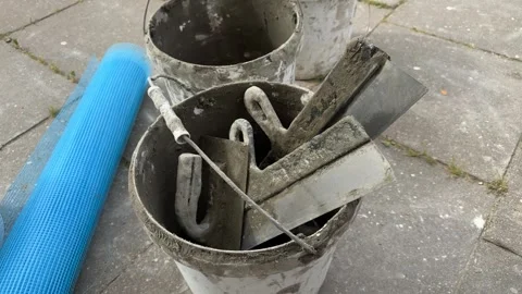 Dirty white buckets filled with plastering tools and blue mesh roll  스톡 동영상 344782567