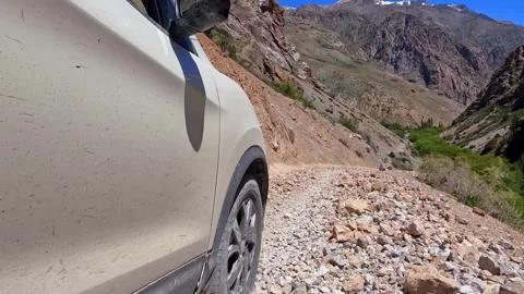Dirty white car is moving down a rocky road in the mountains of Tajikistan Video stock 317169188