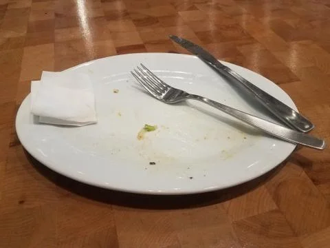 Dirty white plate on table with fork and knife Stock Photos