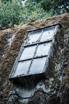 A Dirty Window In A Rusty Frame On A Moss Covered Corrugated Iron Roof Stock Photos